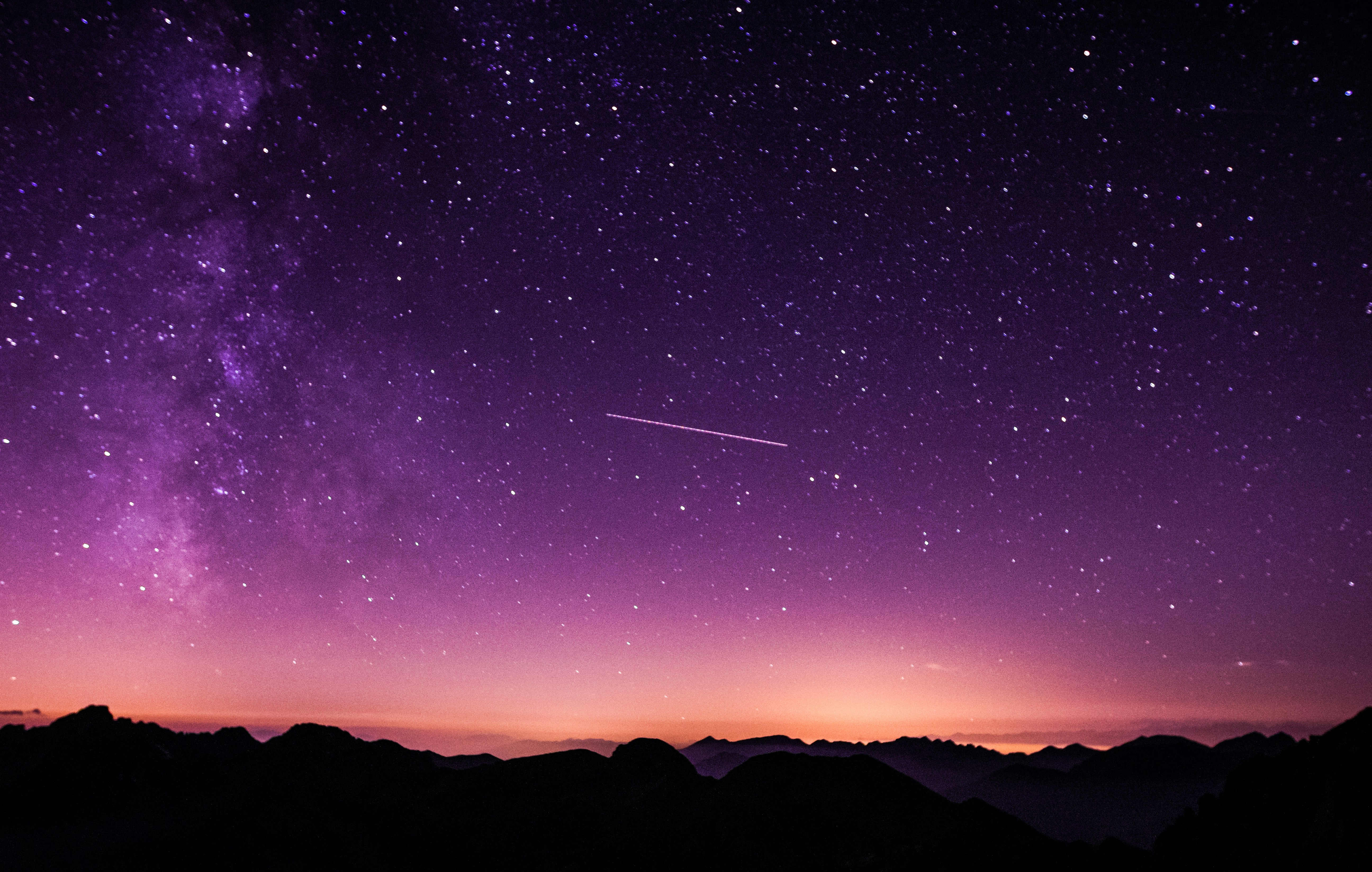 A picture of a sunset with the stars and mountains visible, as well as a shooting star across the center.